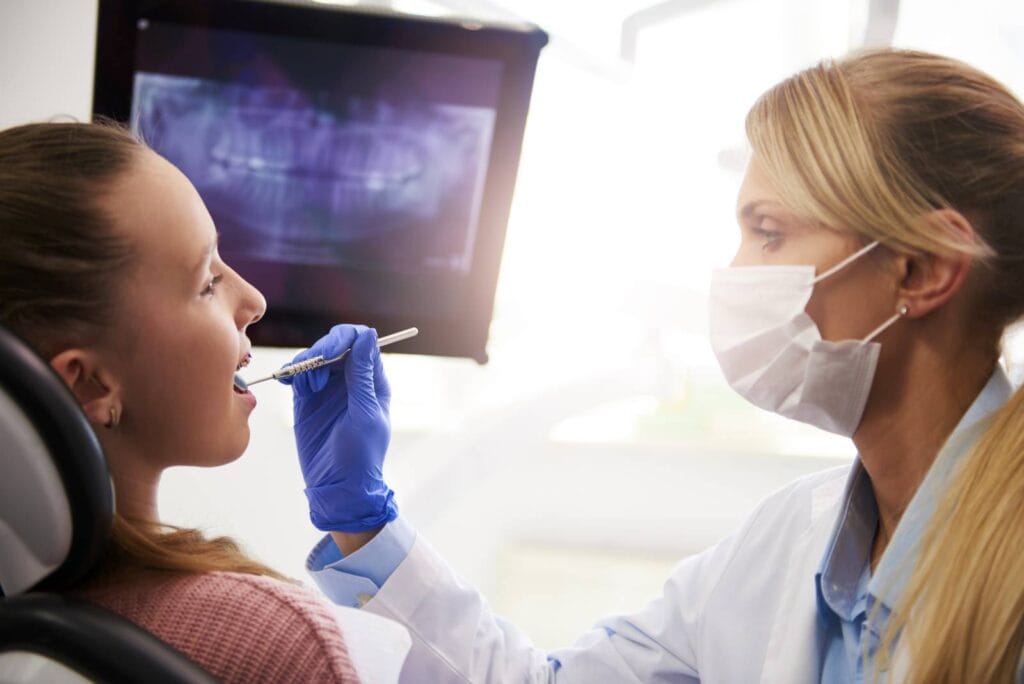 female orthodontist using dental mirror during checkup