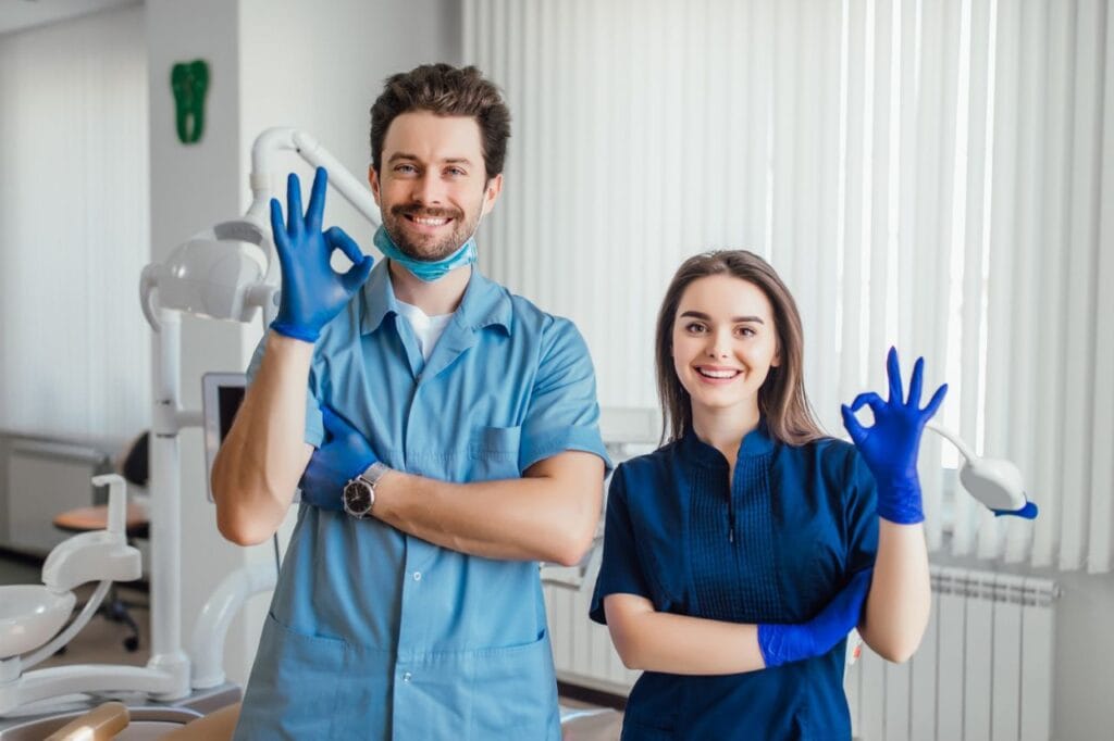 photo smiling dentist standing with arms crossed with her colleague showing okay sign