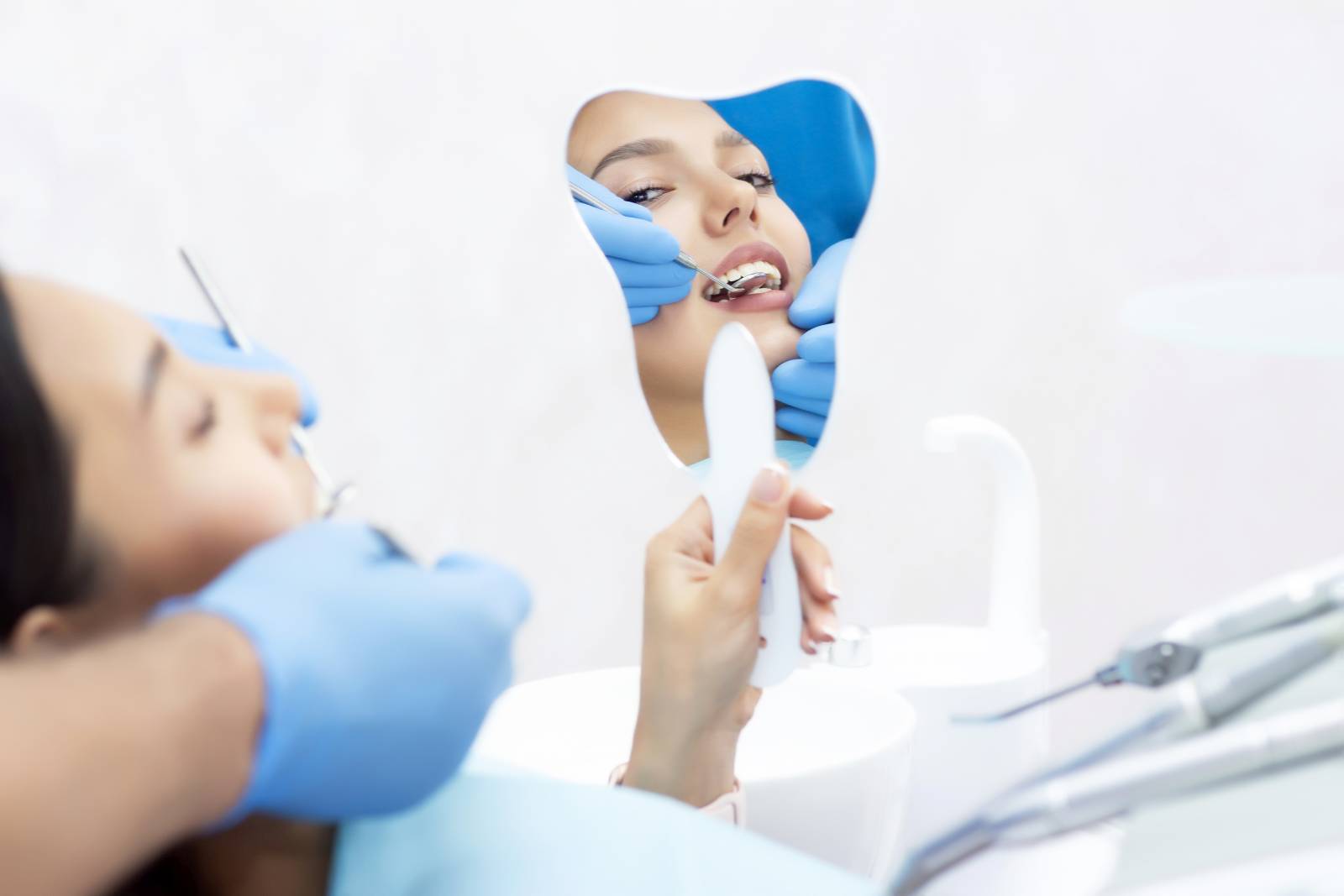 young women checks her teeth in the mirror. young woman in the dentists office. new dental implants.